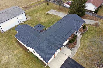 Aerial view of a house and garage with a dark metal roof