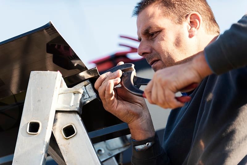 Installer bending metal trim with hand seamers